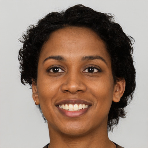 Joyful black young-adult female with short  black hair and brown eyes