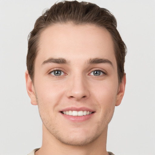 Joyful white young-adult male with short  brown hair and grey eyes