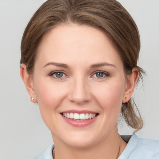 Joyful white young-adult female with medium  brown hair and grey eyes