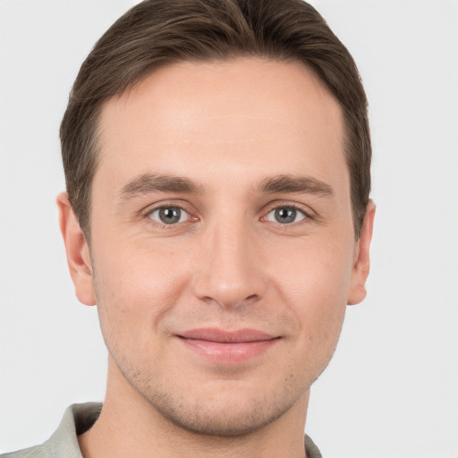 Joyful white young-adult male with short  brown hair and grey eyes