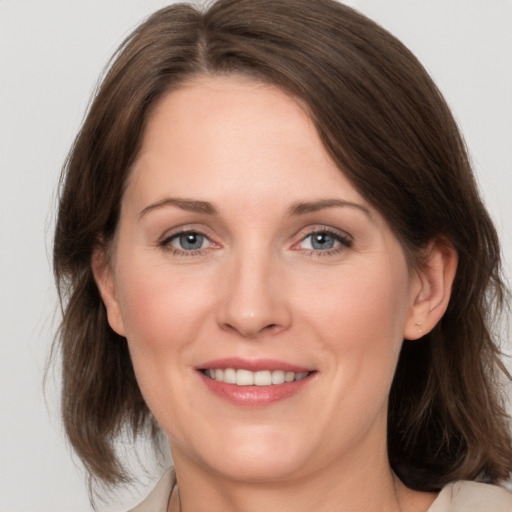 Joyful white young-adult female with medium  brown hair and grey eyes