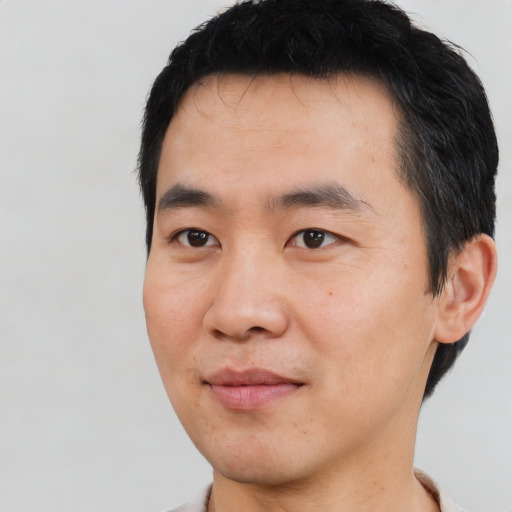 Joyful asian young-adult male with short  black hair and brown eyes