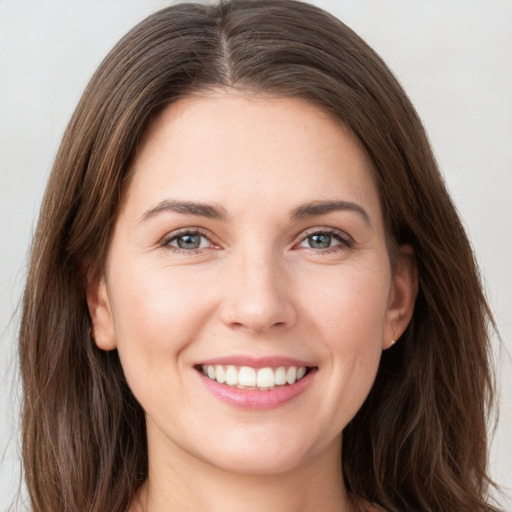 Joyful white young-adult female with long  brown hair and grey eyes