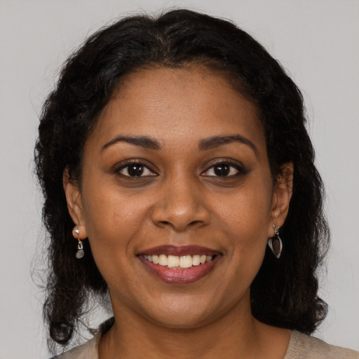 Joyful black young-adult female with long  brown hair and brown eyes