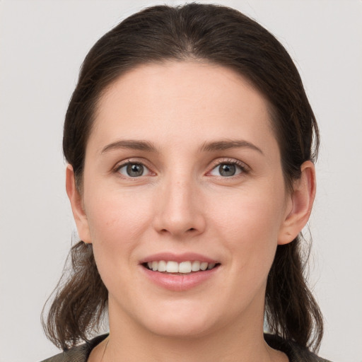 Joyful white young-adult female with medium  brown hair and grey eyes