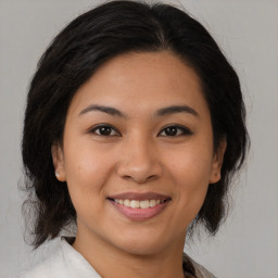 Joyful latino young-adult female with medium  brown hair and brown eyes