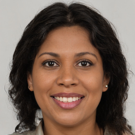 Joyful black young-adult female with long  brown hair and brown eyes