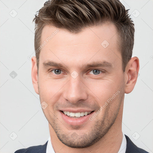 Joyful white young-adult male with short  brown hair and grey eyes