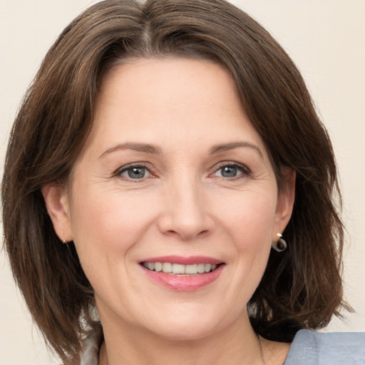 Joyful white adult female with medium  brown hair and grey eyes