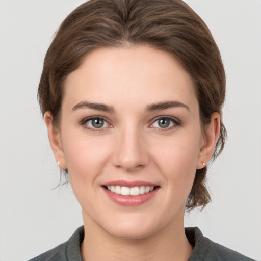 Joyful white young-adult female with medium  brown hair and grey eyes