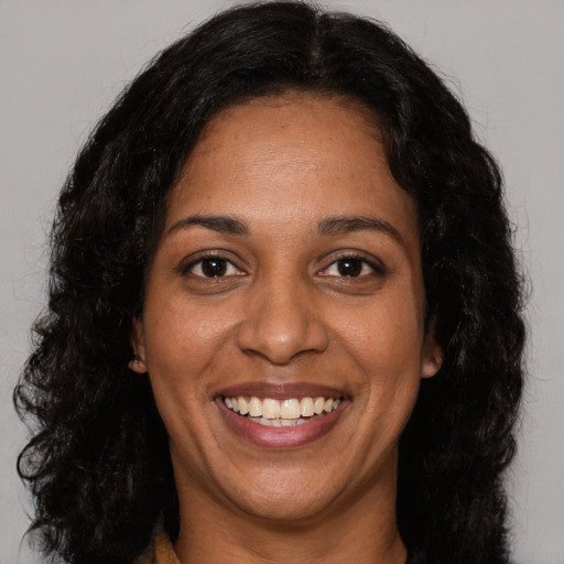 Joyful black young-adult female with long  brown hair and brown eyes