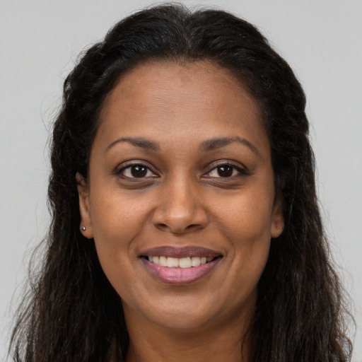 Joyful black adult female with long  brown hair and brown eyes