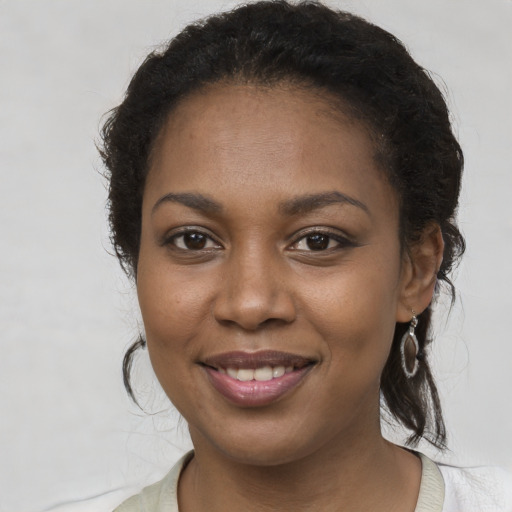 Joyful black young-adult female with long  brown hair and brown eyes