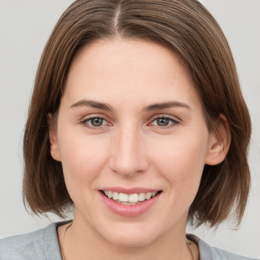 Joyful white young-adult female with medium  brown hair and grey eyes