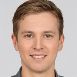 Joyful white young-adult male with short  brown hair and grey eyes