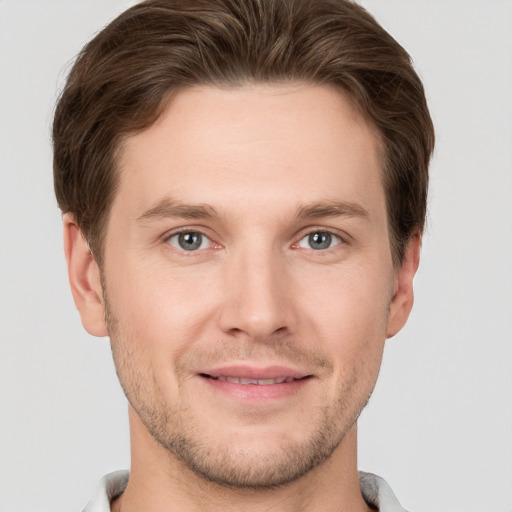 Joyful white young-adult male with short  brown hair and grey eyes