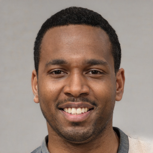Joyful black young-adult male with short  black hair and brown eyes