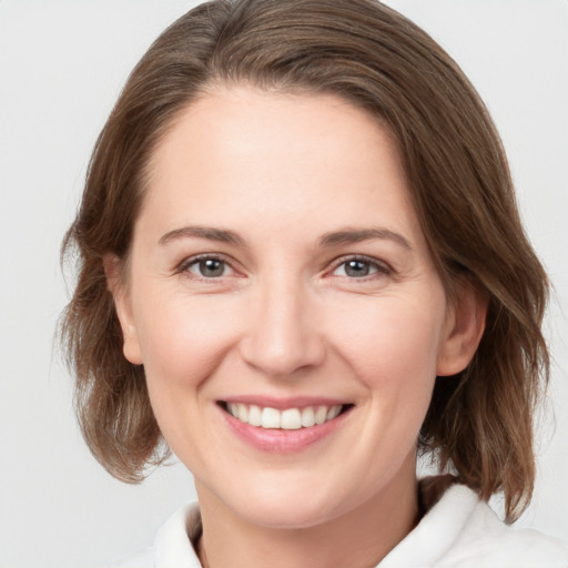 Joyful white young-adult female with medium  brown hair and grey eyes