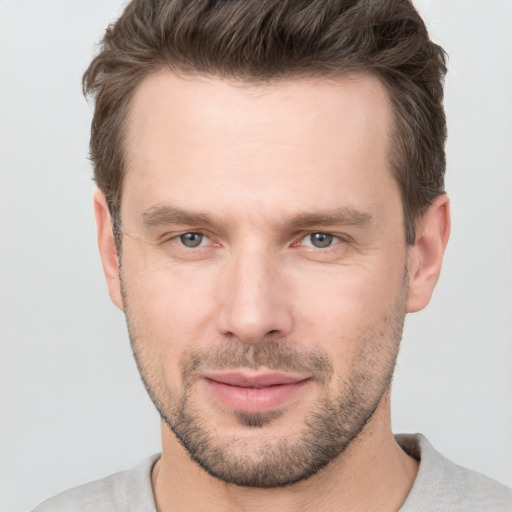 Joyful white young-adult male with short  brown hair and grey eyes