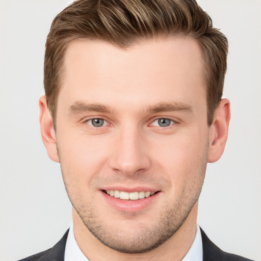 Joyful white young-adult male with short  brown hair and grey eyes