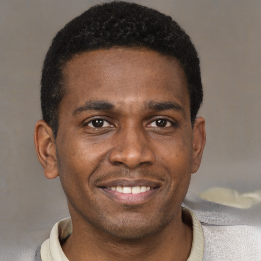 Joyful black young-adult male with short  brown hair and brown eyes