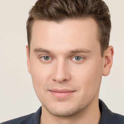 Joyful white young-adult male with short  brown hair and grey eyes