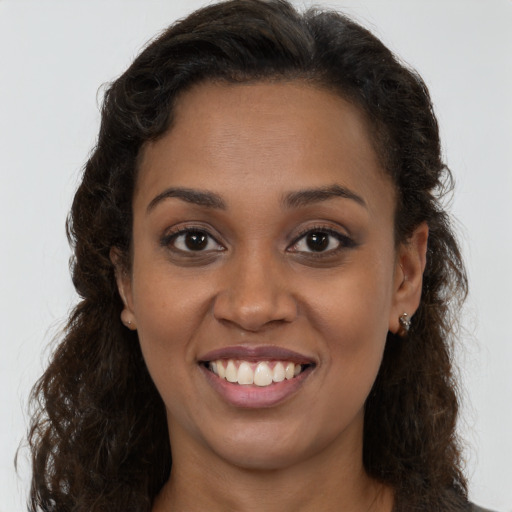 Joyful black young-adult female with long  brown hair and brown eyes