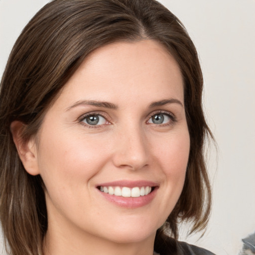 Joyful white young-adult female with medium  brown hair and grey eyes