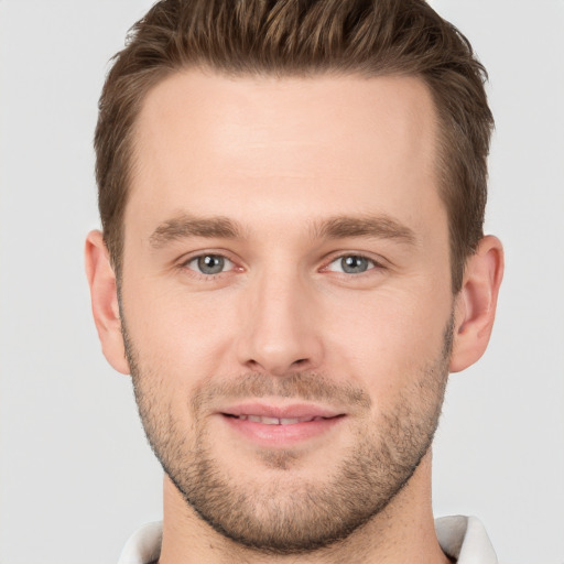 Joyful white young-adult male with short  brown hair and grey eyes