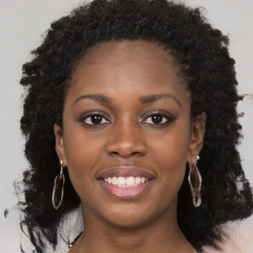 Joyful black young-adult female with long  brown hair and brown eyes