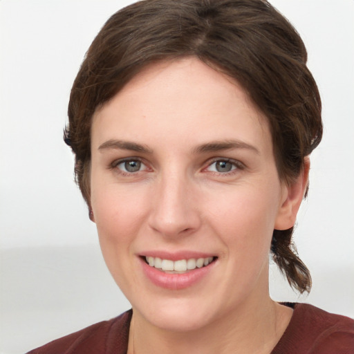 Joyful white young-adult female with medium  brown hair and grey eyes