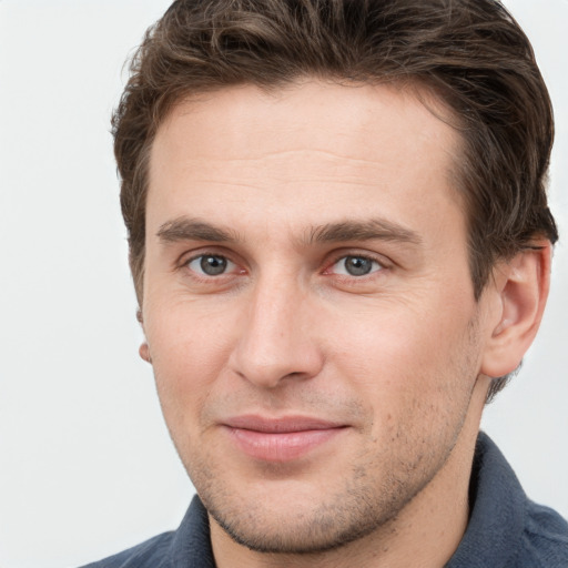 Joyful white young-adult male with short  brown hair and grey eyes