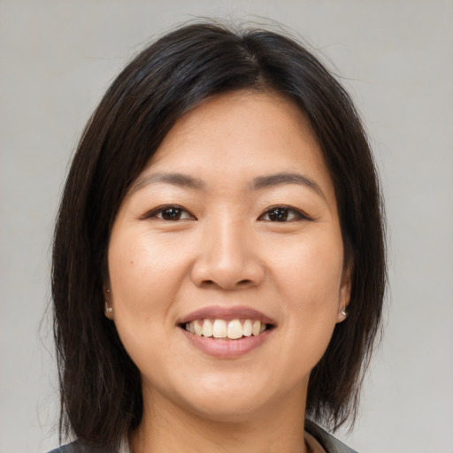 Joyful asian young-adult female with medium  brown hair and brown eyes
