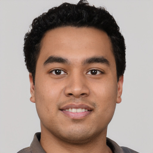Joyful latino young-adult male with short  black hair and brown eyes