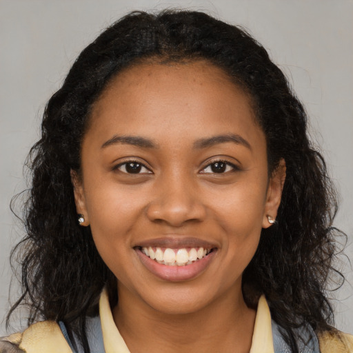 Joyful black young-adult female with long  brown hair and brown eyes