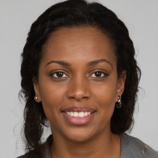 Joyful black young-adult female with long  brown hair and brown eyes