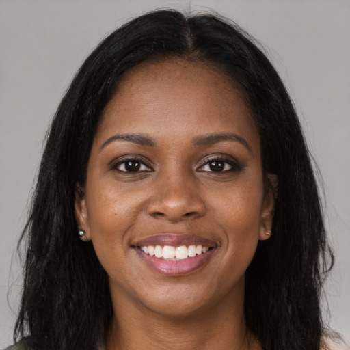 Joyful black young-adult female with long  brown hair and brown eyes