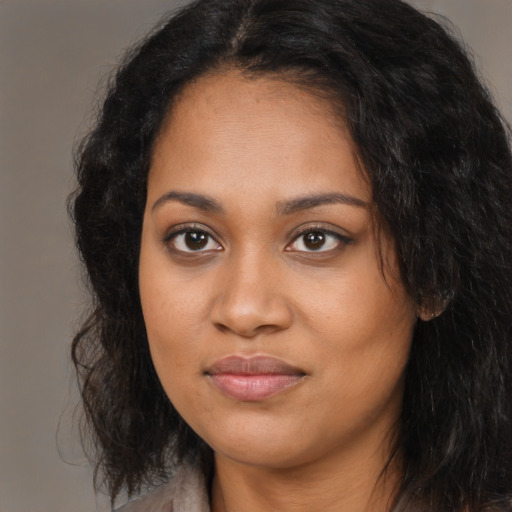 Joyful black young-adult female with long  brown hair and brown eyes
