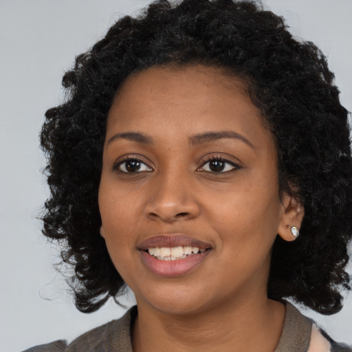 Joyful black young-adult female with long  black hair and brown eyes