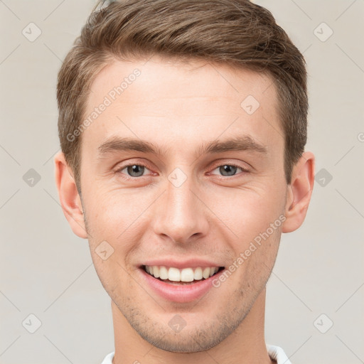 Joyful white young-adult male with short  brown hair and grey eyes