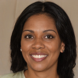 Joyful black young-adult female with long  brown hair and brown eyes