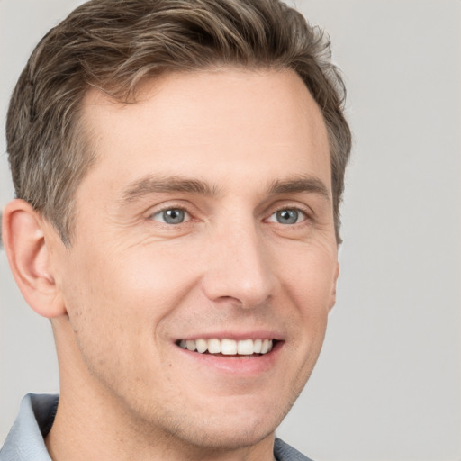 Joyful white young-adult male with short  brown hair and grey eyes