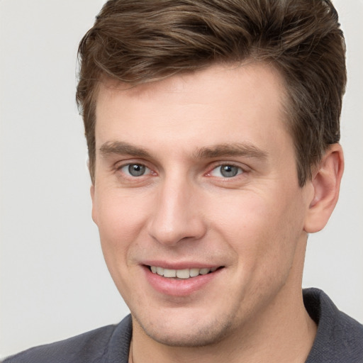 Joyful white young-adult male with short  brown hair and grey eyes