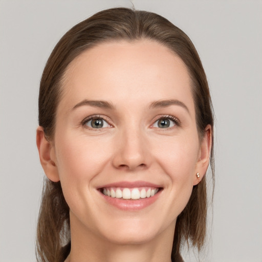 Joyful white young-adult female with medium  brown hair and grey eyes