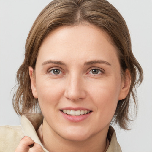 Joyful white young-adult female with medium  brown hair and grey eyes