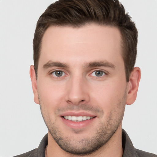 Joyful white young-adult male with short  brown hair and grey eyes