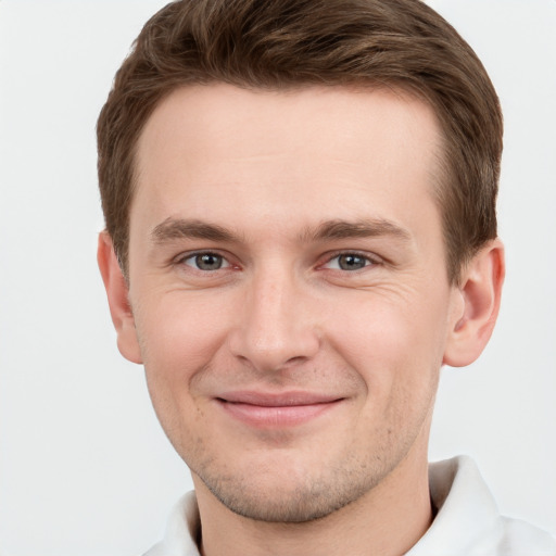 Joyful white young-adult male with short  brown hair and grey eyes