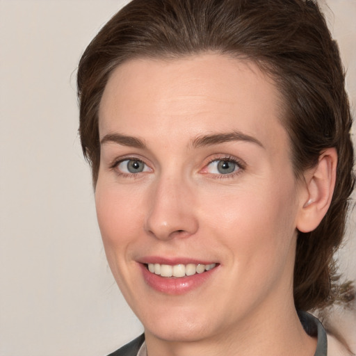 Joyful white young-adult female with medium  brown hair and grey eyes