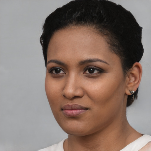 Joyful black young-adult female with short  black hair and brown eyes