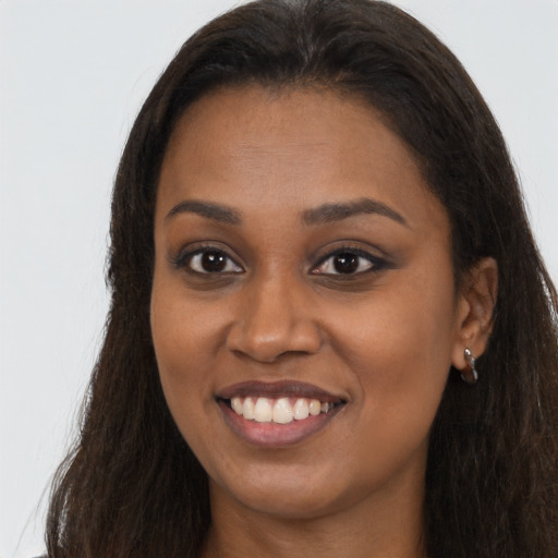 Joyful black young-adult female with long  brown hair and brown eyes